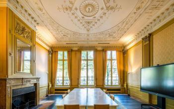 Elegant office space with ornate ceiling and large windows at Herengracht 582-584, Amsterdam Canal Belt, perfect for office space rental. Furnished with a long table and chairs, ideal for meetings.