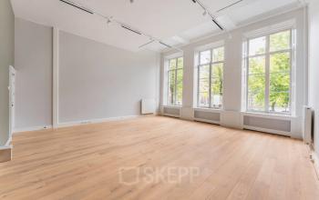Spacious office to rent at Herengracht 582-584 in the Amsterdam Canal Belt, featuring large windows and wooden flooring, perfect for office space rental.