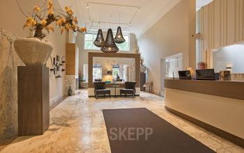 Elegant reception area with marble floors, high ceilings, modern decor, and seating at Herengracht 448-458, Amsterdam Canal Belt, Amsterdam. This office space rental offers a sophisticated welcome environment.
