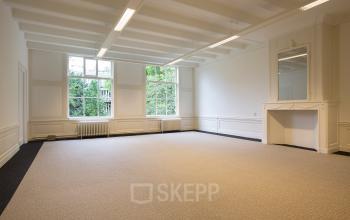 Spacious, unfurnished office space with large windows and a decorative fireplace located at Herengracht 448-458 in Amsterdam Canal Belt.