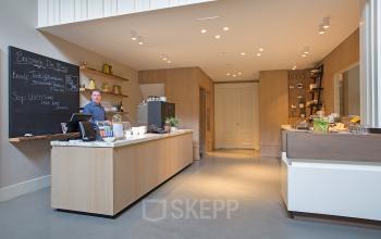 Reception area at Herengracht 448-458 in Amsterdam Canal Belt, featuring a modern wooden counter with a person standing behind it, offering office space rental.