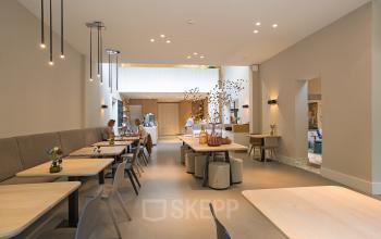 Modern office space at Herengracht 448-458 in Amsterdam Canal Belt, featuring contemporary furniture, tables, and people engaging in business activities.