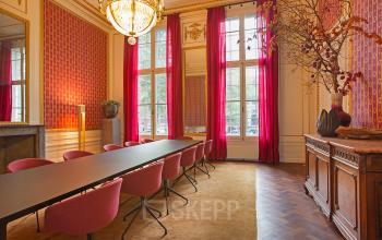 Elegant conference room with large windows, chandeliers, and long table with red chairs at Herengracht 448-458, in Amsterdam Canal Belt.