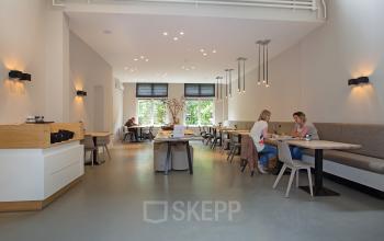 Modern office at Herengracht 448-458 in Amsterdam Canal Belt with bright lighting and people engaged in business activities at communal tables.