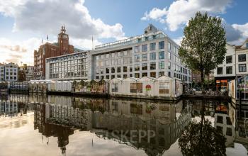 Exterior view of an office building at Singel 542, in Amsterdam Canal Belt, reflecting in the canal, ideal for rent office space seekers.