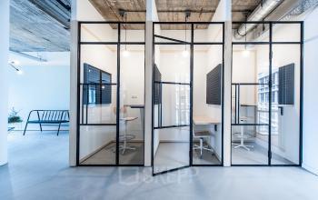 Modern office cubicles for rent at Singel 542, Amsterdam Canal Belt, featuring minimalistic furnishings and industrial design elements.
