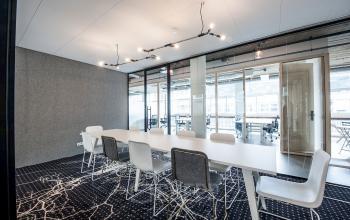 Bright office space with modern furnishings, featuring a long table and chairs, available for rent in Amsterdam Canal Belt.
