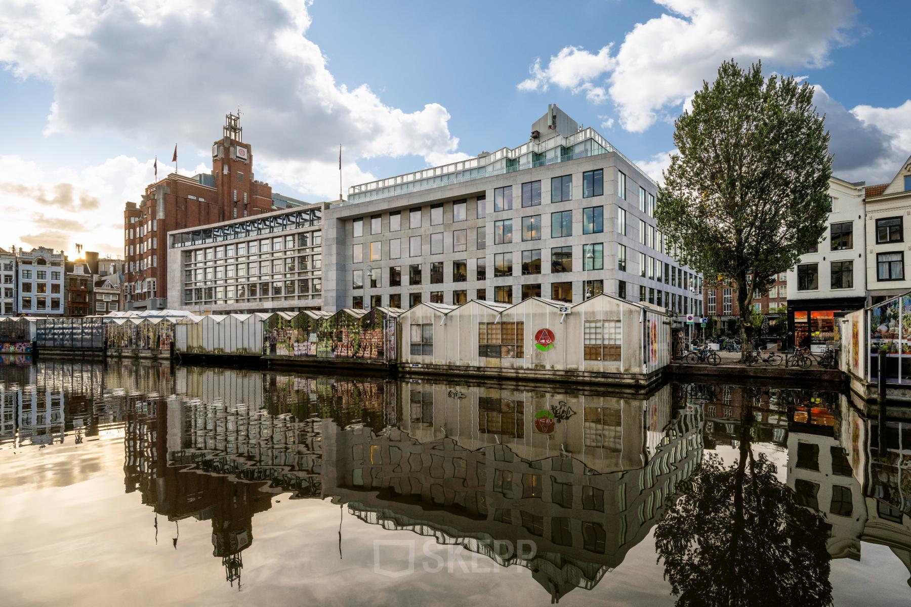 Exterior view of an office building at Singel 542, in Amsterdam Canal Belt, reflecting in the canal, ideal for rent office space seekers.