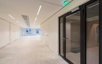 Empty office space available for rent at Herengracht 459-469, Amsterdam Canal Belt, featuring large windows and modern lighting.