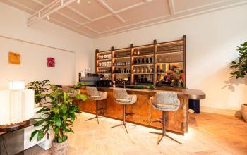 Elegant workspace at Keizersgracht 264, Amsterdam Canal Belt, featuring a stylish bar area with seating and decorative plants, ideal for office space rental.