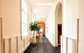 Bright hallway in a Keizersgracht 264 office to rent, featuring large windows and potted plants, offering a welcoming space for office space rental.
