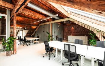 Spacious office space for rent in Amsterdam Canal Belt with modern furnishings, skylights, and exposed beams, providing a dynamic work environment.