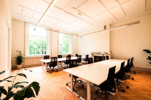 Furnished office space with desks and chairs ideal for rent at Keizersgracht 264, offering a bright workspace with large windows in Amsterdam Canal Belt.