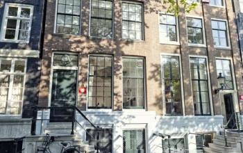 Exterior view of historic office space rental at Keizersgracht 97-99 in Amsterdam Canal Belt, featuring classic architecture with large windows.