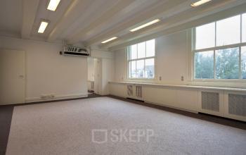 Bright, unfurnished office space rental at Herengracht 495, Amsterdam, featuring large windows, high ceilings, and ample natural light.