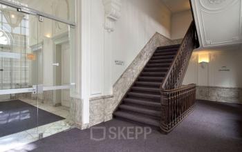 Elegant staircase and entrance area in an Amsterdam Canal Belt office building at Herengracht 495, featuring marble detailing and glass doors, ideal for office space rental.