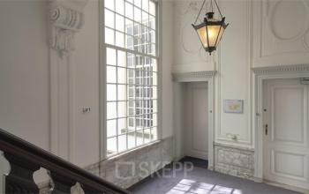 Interior view of Herengracht 495 office space rental, featuring a grand staircase, marble details, and an elegant hanging light in the Amsterdam Canal Belt.