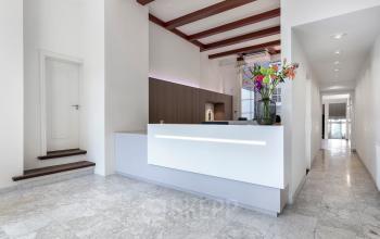 Modern reception area at Keizersgracht 106, Amsterdam Canal Belt, featuring a sleek desk, marble flooring, and a flower arrangement.