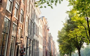 Keizersgracht 106 office building along the Amsterdam Canal Belt, featuring historic architecture with lush greenery lining the street, suitable for office space rental.