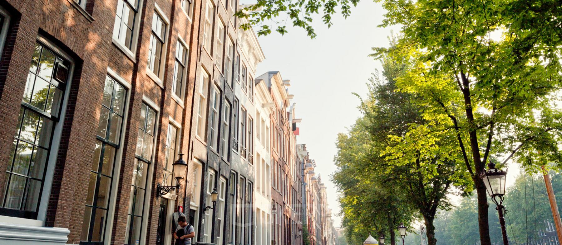 Keizersgracht 106 office building along the Amsterdam Canal Belt, featuring historic architecture with lush greenery lining the street, suitable for office space rental.