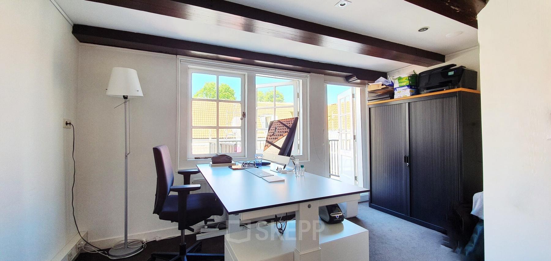 Office space with a desk, computer, and minimal furnishings at Keizersgracht 106 in Amsterdam Canal Belt.
