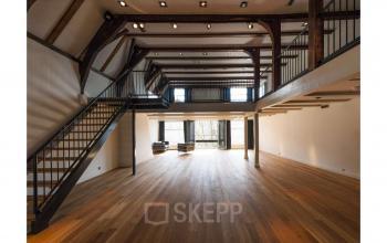 Spacious interior with high ceilings and wooden floors at Herengracht 168, Amsterdam Canal Belt. Ideal for office space rental with an elegant mezzanine and ample natural light.