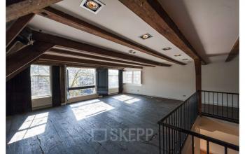Spacious loft-style office to rent at Herengracht 168, Amsterdam Canal Belt. Features wooden beams, large windows, and open floor plan ideal for creative projects.