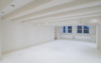 Spacious and well-lit office space rental at Herengracht 168 in Amsterdam Canal Belt, featuring white walls and large windows.