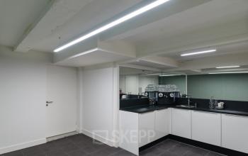 Modern office space rental at Herengracht 168, Amsterdam Canal Belt, featuring a sleek kitchenette with black countertops.