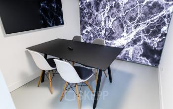 Office space rental at Herengracht 168, Amsterdam, featuring a sleek meeting area with a striking marble backdrop and modern furnishings.