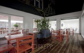 Spacious and well-lit office space rental at Herengracht 124-128, Amsterdam Canal Belt, featuring a sleek wooden floor and modern furnishings.