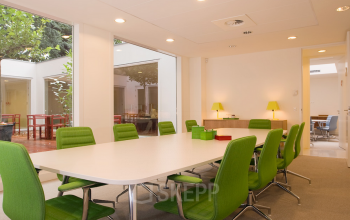 Bright office space rental at Herengracht 124-128 in Amsterdam Canal Belt featuring a large conference table with green chairs and ample lighting.