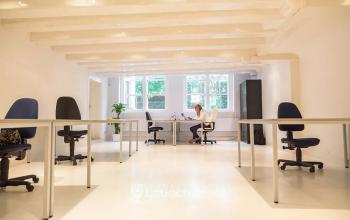 Spacious and well-lit office space rental at Herengracht 124-128, Amsterdam Canal Belt, with a person focused on work at a desk.