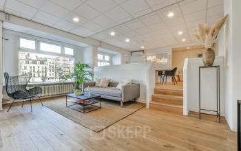 Elegantly furnished lounge area within the office to rent at Amstel 62, featuring comfortable seating and chic decor, with views of the Amsterdam Canal Belt.
