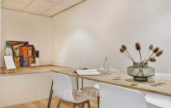 Stylish office space rental at Amstel 62, Amsterdam Canal Belt, featuring a wooden desk, modern chairs, and vibrant artwork.