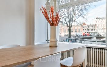 Office space rental at Amstel 62 overlooking Amsterdam Canal Belt with a stylish table and large windows.