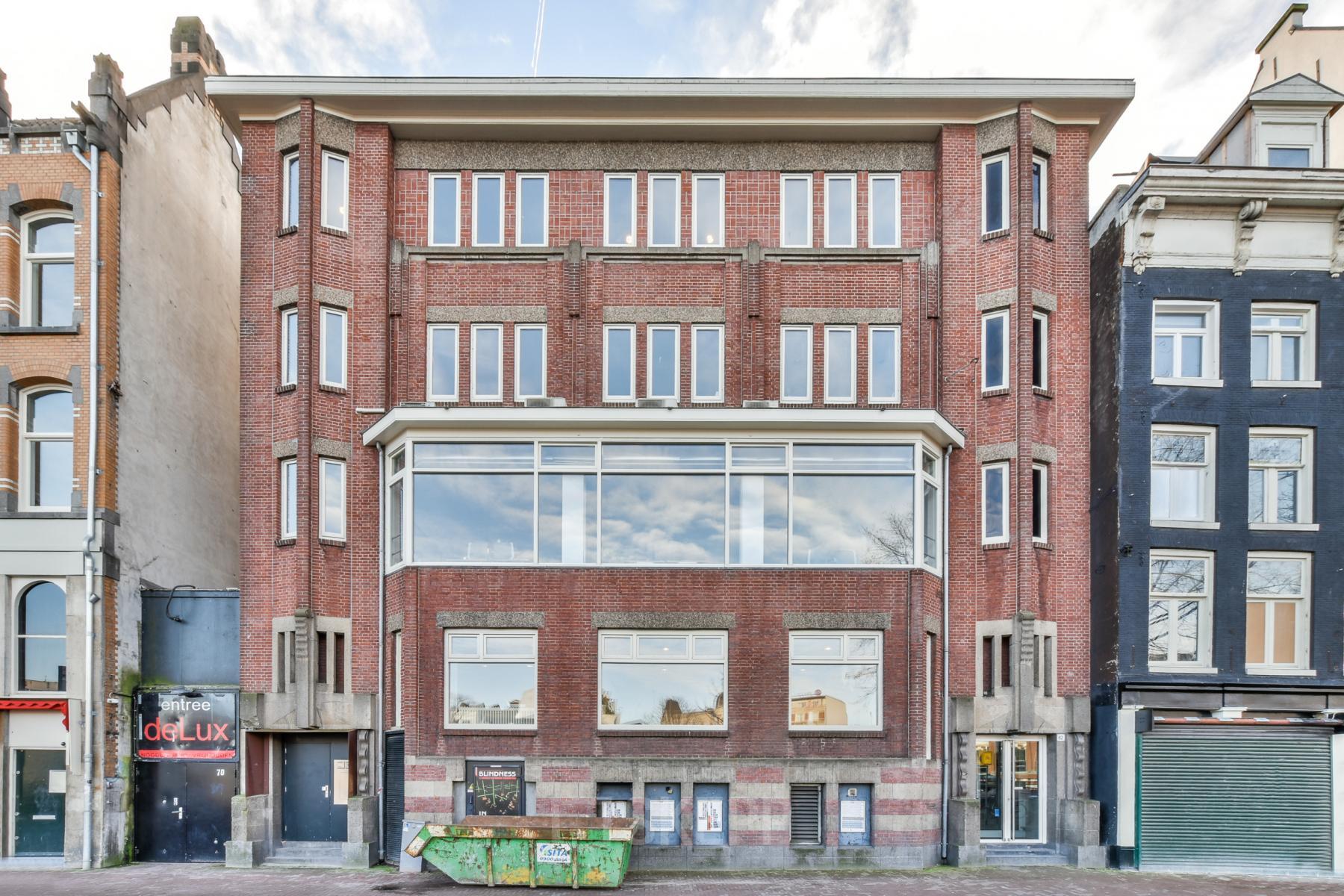 Modern office space rental at Amstel 62, situated in Amsterdam Canal Belt, with large windows overlooking the canal.