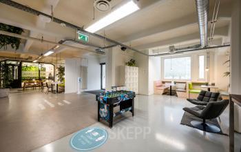 Spacious office interior in Amsterdam Houthavens featuring a foosball table, seating areas, and meeting space available for office space rental.