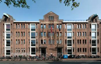 Exterior view of the Van Diemenstraat 20-200 office building in Amsterdam Houthavens, showing the red-brick facade and bicycles lined up at the front, ideal for office space rental.