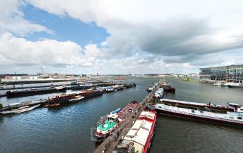Scenic view of Amsterdam Houthavens with various boats docked along the waterfront, offering a dynamic backdrop for those seeking office space rental.