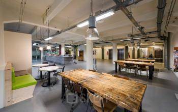 Spacious and modern office to rent in Amsterdam Houthavens, featuring wooden tables, seating areas, and a central open plan layout ideal for collaborative work.
