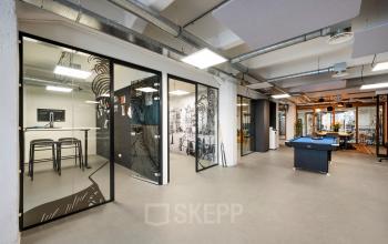 Spacious office with a billiards table, glass-walled conference rooms, and modern decor. Ideal for office space rental at Van Diemenstraat 20-200, Amsterdam Houthavens.