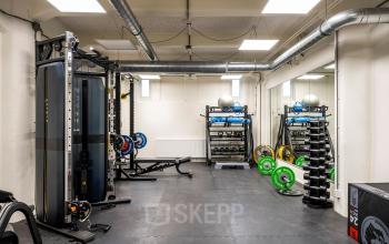 Spacious gym area with various workout equipment and mirrors at the office space rental in Van Diemenstraat, Amsterdam Houthavens.
