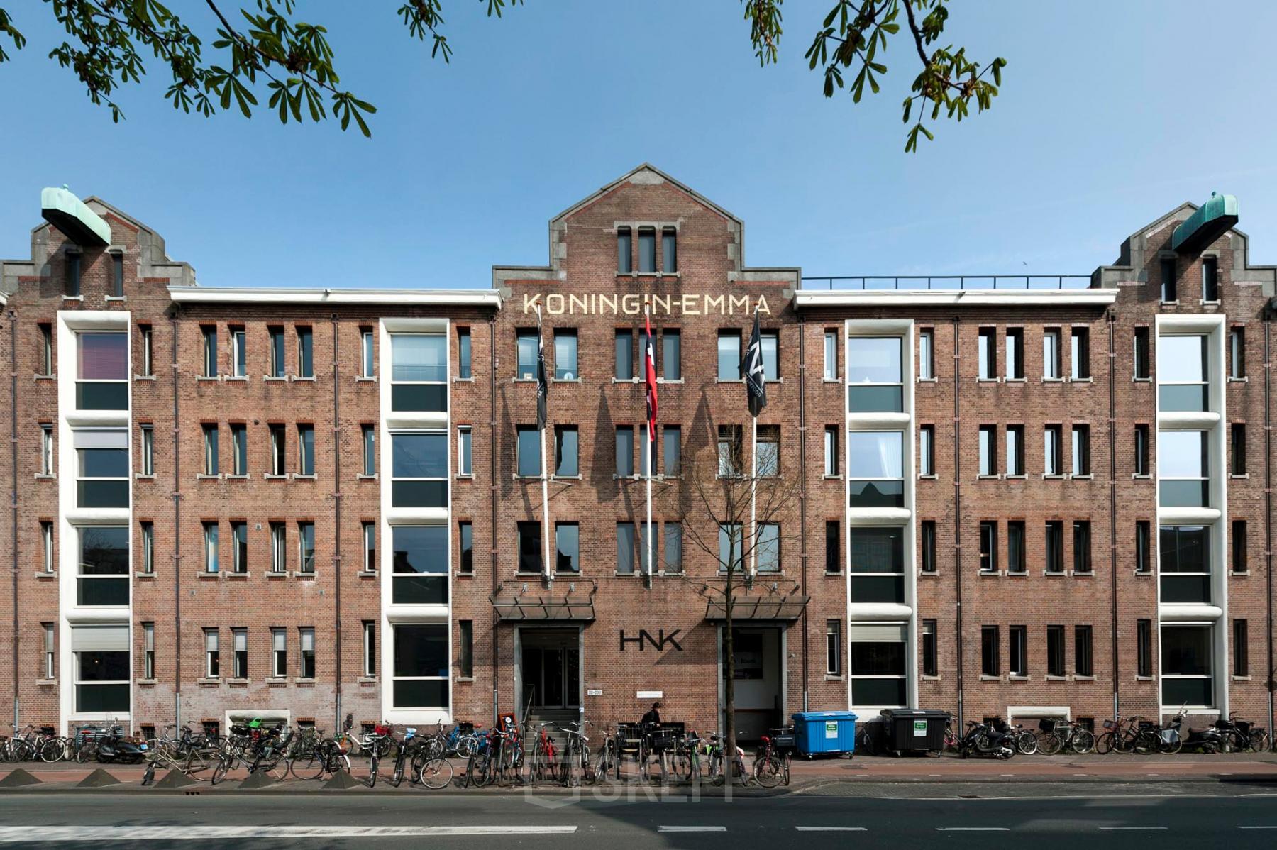 Exterior view of the Van Diemenstraat 20-200 office building in Amsterdam Houthavens, showing the red-brick facade and bicycles lined up at the front, ideal for office space rental.