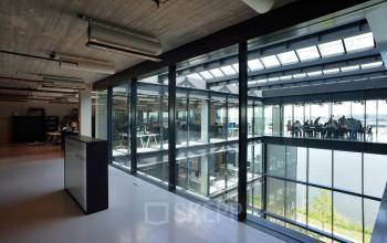 Modern office interior at Moermanskkade 109-113, Amsterdam Houthavens, featuring a spacious open floor plan with large windows and natural light. Ideal for office space rental.