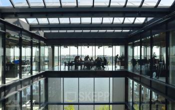 Spacious modern interior view at Moermanskkade 109-113, Amsterdam Houthavens, showcasing an open-floor design with a glass ceiling offering natural light, ideal for office space rental.