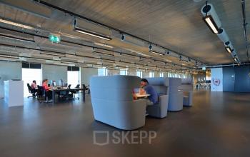 Contemporary office space rental at Moermanskkade 109-113, Amsterdam Houthavens, featuring modern desks and casual seating areas with people engaged in work activities.