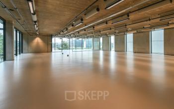 Spacious, unfurnished interior of an office for rent, featuring a modern industrial design with large windows and high ceilings, located at Moermanskkade 109-113 in Amsterdam Houthavens.