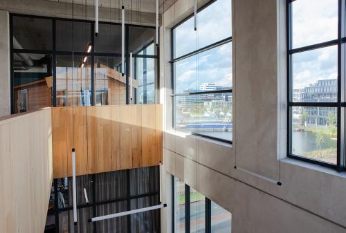 Modern office interior at Danzigerbocht 39 in Amsterdam Houthavens with large windows, high ceilings, and wooden accents.