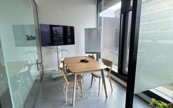 Bright office space at Amsterdam Houthavens with a table, chairs, TV, and a flip chart, ideal for meetings. Suitable for those looking to rent office space with a modern touch.